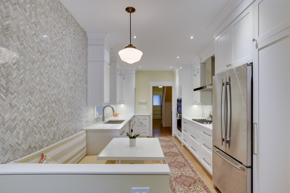 Example of a mid-sized classic galley medium tone wood floor kitchen design in Toronto with an undermount sink, shaker cabinets, white cabinets, quartz countertops, gray backsplash, stone tile backsplash, stainless steel appliances and no island