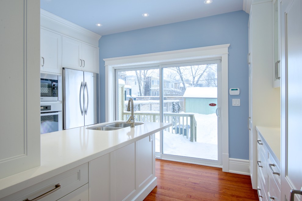 Design ideas for a small victorian u-shaped enclosed kitchen in Toronto with a submerged sink, beaded cabinets, white cabinets, engineered stone countertops, multi-coloured splashback, matchstick tiled splashback, stainless steel appliances, medium hardwood flooring and a breakfast bar.