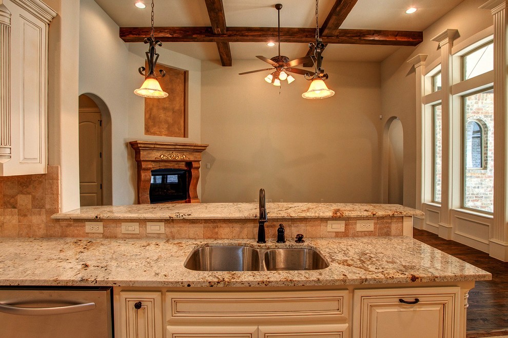 Inspiration for a mid-sized timeless galley ceramic tile open concept kitchen remodel in Dallas with an undermount sink, raised-panel cabinets, white cabinets, granite countertops, beige backsplash, ceramic backsplash, stainless steel appliances and a peninsula