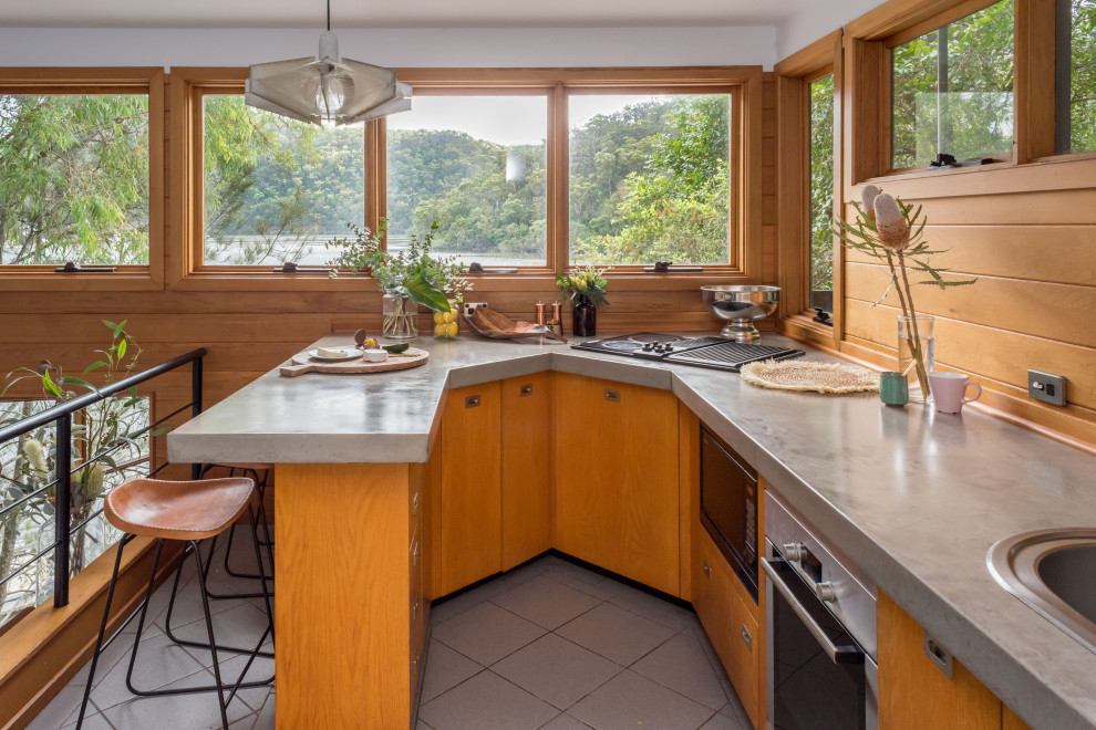 Immagine di una piccola cucina ad U tropicale con lavello da incasso, ante lisce, ante in legno scuro, penisola, pavimento grigio e top grigio