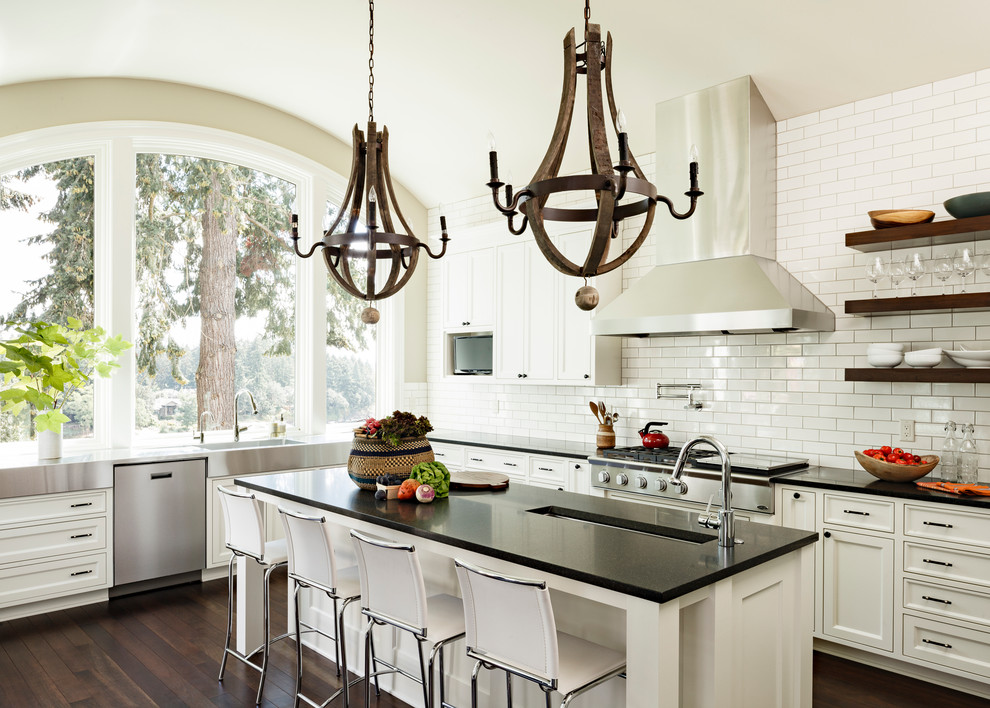 Large trendy l-shaped dark wood floor and brown floor kitchen photo in Portland with granite countertops, recessed-panel cabinets, white cabinets, white backsplash, subway tile backsplash, stainless steel appliances, an undermount sink and an island