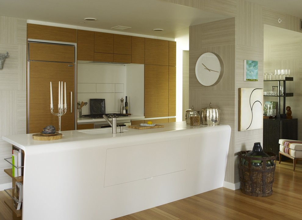 На фото: параллельная кухня-гостиная в стиле модернизм с плоскими фасадами, светлыми деревянными фасадами, столешницей из акрилового камня, техникой под мебельный фасад и обоями на стенах с