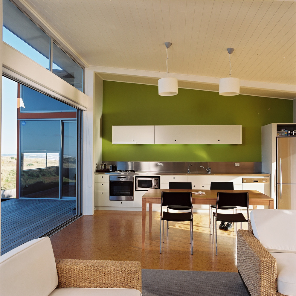 Exempel på ett mellanstort modernt linjärt kök med öppen planlösning, med bänkskiva i rostfritt stål, grönt stänkskydd, rostfria vitvaror och plywoodgolv