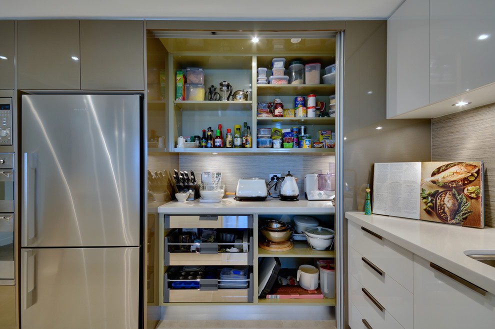 Diseño de cocina actual con armarios con paneles lisos, puertas de armario blancas y electrodomésticos de acero inoxidable