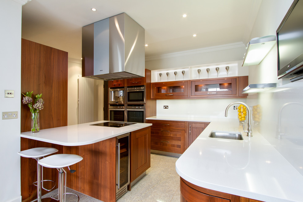Foto på ett funkis l-kök, med en undermonterad diskho, skåp i shakerstil, skåp i mellenmörkt trä, vitt stänkskydd och rostfria vitvaror