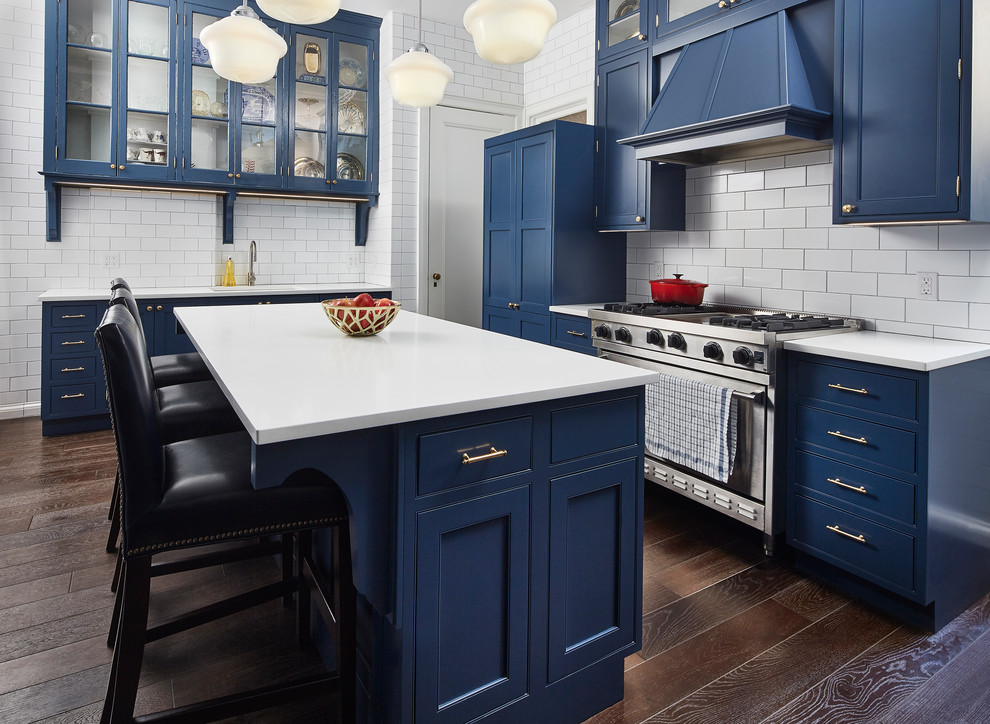 Idéer för mellanstora funkis u-kök, med en undermonterad diskho, luckor med infälld panel, blå skåp, bänkskiva i kvartsit, vitt stänkskydd, stänkskydd i tunnelbanekakel, rostfria vitvaror, mörkt trägolv, en köksö och brunt golv