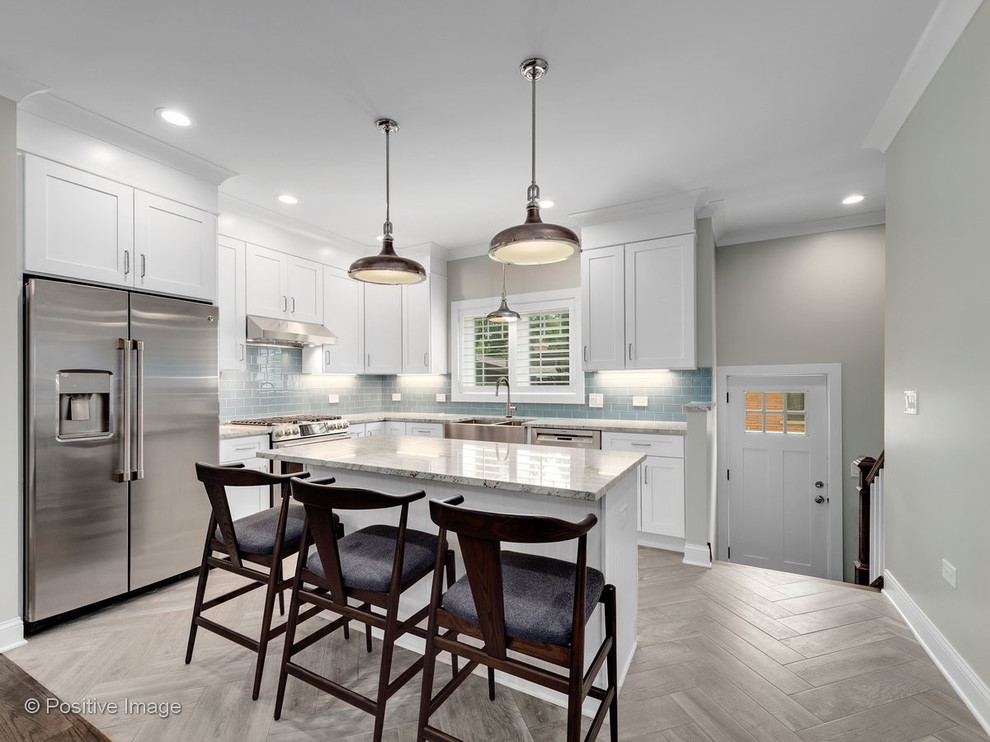 Example of a mid-sized transitional l-shaped porcelain tile and gray floor open concept kitchen design in Chicago with a farmhouse sink, shaker cabinets, white cabinets, granite countertops, blue backsplash, glass tile backsplash, stainless steel appliances, an island and gray countertops