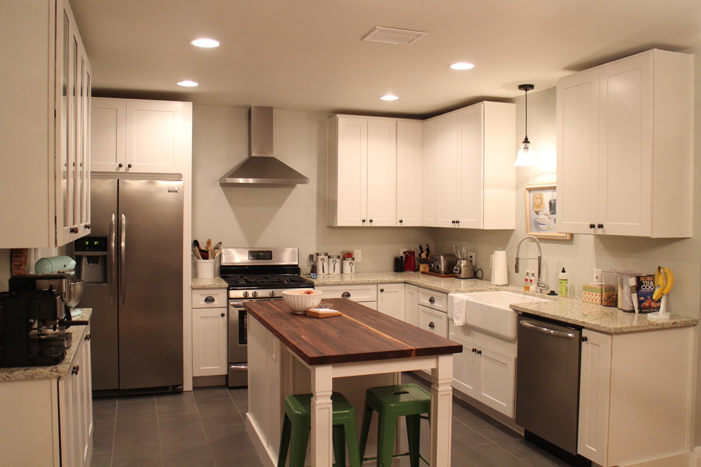 Exempel på ett mellanstort lantligt kök, med en rustik diskho, luckor med infälld panel, vita skåp, träbänkskiva, grått stänkskydd, rostfria vitvaror, klinkergolv i porslin och en köksö