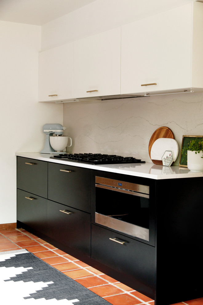 Inredning av ett retro mellanstort vit vitt kök, med en undermonterad diskho, släta luckor, svarta skåp, bänkskiva i kvarts, vitt stänkskydd, svarta vitvaror, klinkergolv i terrakotta och rött golv