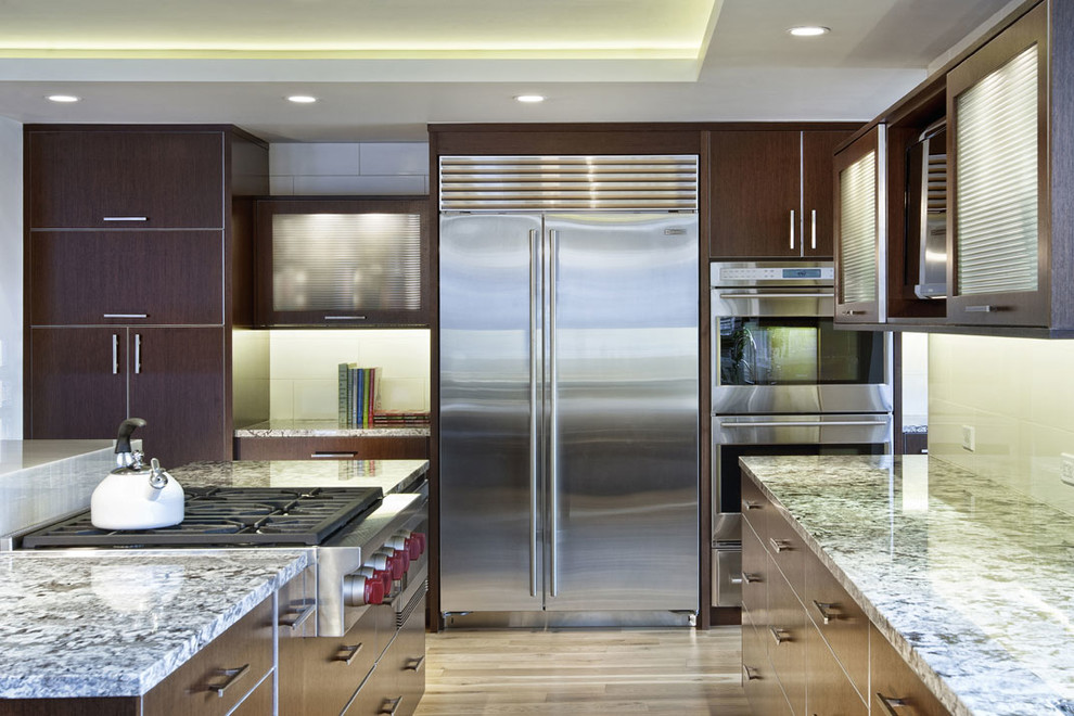 Example of a trendy l-shaped eat-in kitchen design in Denver with flat-panel cabinets, dark wood cabinets, granite countertops, white backsplash, subway tile backsplash and stainless steel appliances