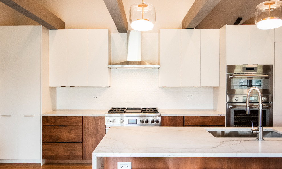 Bild på ett stort retro vit vitt kök, med en undermonterad diskho, släta luckor, skåp i mellenmörkt trä, bänkskiva i kvartsit, vitt stänkskydd, stänkskydd i mosaik, integrerade vitvaror, mellanmörkt trägolv, en köksö och brunt golv