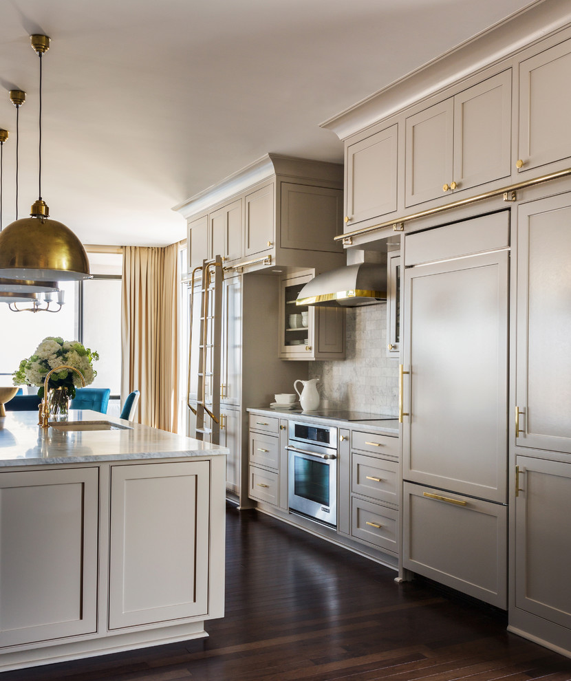 Example of a large transitional galley medium tone wood floor open concept kitchen design in Little Rock with recessed-panel cabinets, beige cabinets, marble countertops, gray backsplash, paneled appliances and an island