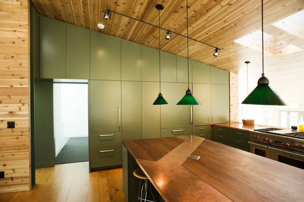 Foto på ett stort funkis kök, med en dubbel diskho, gröna skåp, bänkskiva i akrylsten, rostfria vitvaror, mellanmörkt trägolv och en köksö