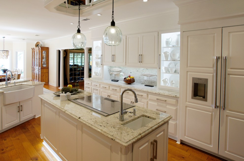 Inspiration for a large timeless u-shaped light wood floor eat-in kitchen remodel in Atlanta with a farmhouse sink, raised-panel cabinets, white cabinets, granite countertops, multicolored backsplash, stone slab backsplash, stainless steel appliances and an island