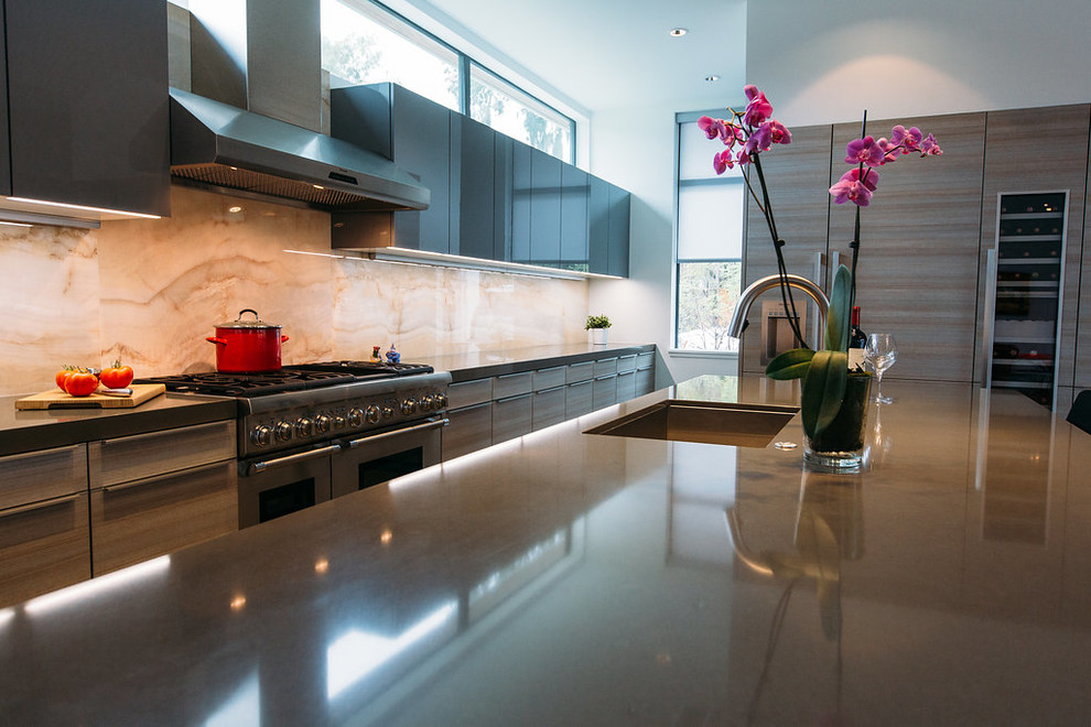 Foto di una cucina minimalista di medie dimensioni con lavello sottopiano, ante lisce, ante grigie, top in quarzo composito, elettrodomestici da incasso e pavimento in cemento