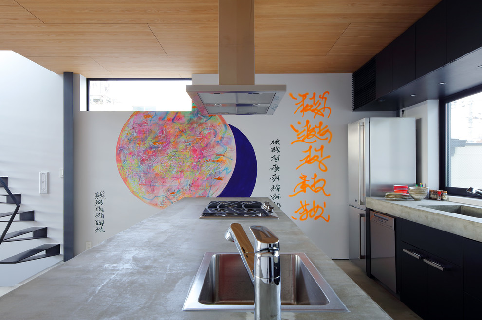 Exemple d'une cuisine parallèle asiatique avec un évier intégré, un placard à porte plane, des portes de placard noires, un plan de travail en béton, fenêtre, un électroménager en acier inoxydable, îlot et un plan de travail gris.