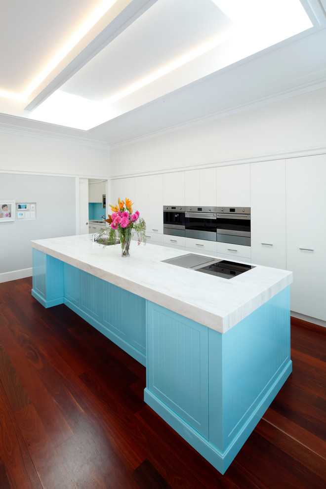 Zweizeilige, Große Moderne Küche mit Unterbauwaschbecken, blauen Schränken, Küchengeräten aus Edelstahl, dunklem Holzboden, Kücheninsel, rotem Boden, weißer Arbeitsplatte und flächenbündigen Schrankfronten in Sydney
