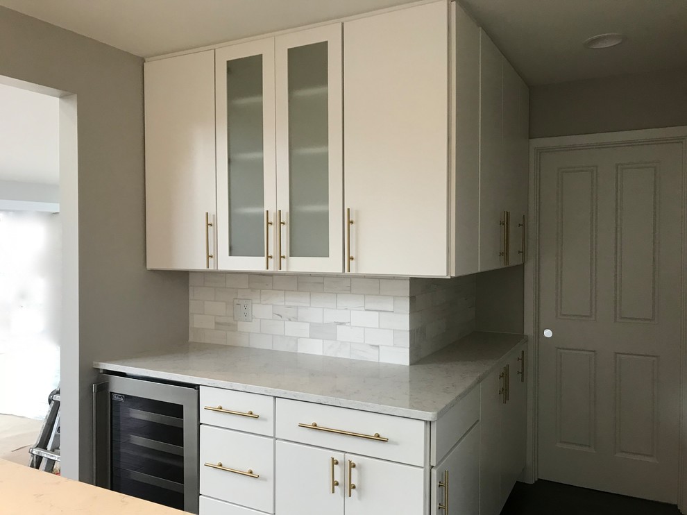 Kitchen pantry - mid-sized modern l-shaped dark wood floor and black floor kitchen pantry idea in Cincinnati with flat-panel cabinets, an island, a farmhouse sink, white cabinets, quartz countertops, gray backsplash, marble backsplash, stainless steel appliances and gray countertops
