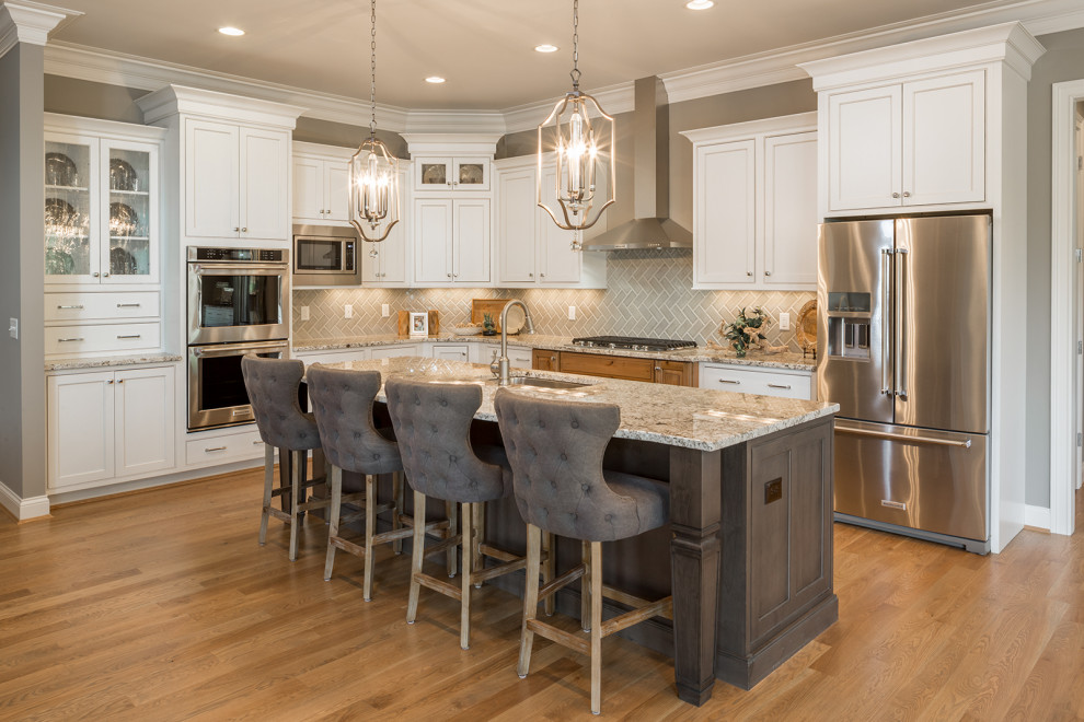 Large traditional l-shaped kitchen in Cincinnati with a submerged sink, shaker cabinets, white cabinets, green splashback, porcelain splashback, stainless steel appliances, medium hardwood flooring, an island, brown floors and grey worktops.