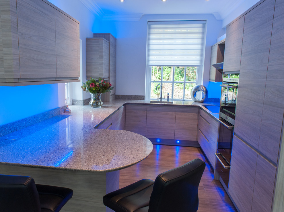 Immagine di una cucina moderna di medie dimensioni con lavello integrato, ante lisce, ante in legno chiaro, top in granito, elettrodomestici in acciaio inossidabile e nessuna isola