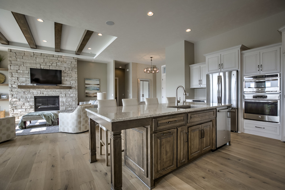 Example of a large transitional l-shaped medium tone wood floor and beige floor open concept kitchen design in Omaha with an undermount sink, raised-panel cabinets, white cabinets, granite countertops, beige backsplash, matchstick tile backsplash, stainless steel appliances and an island