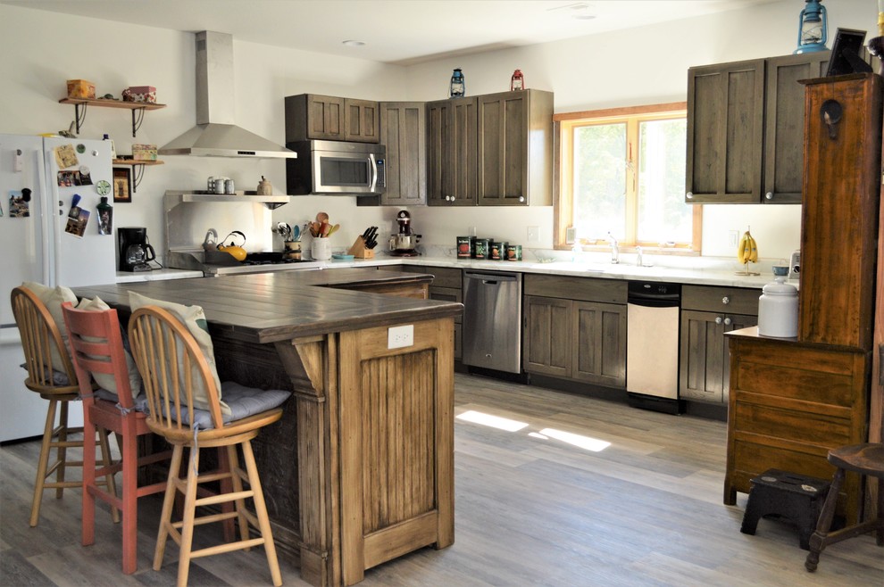 Rustik inredning av ett stort vit vitt kök, med en nedsänkt diskho, luckor med infälld panel, grå skåp, laminatbänkskiva, rostfria vitvaror, laminatgolv, en köksö och brunt golv