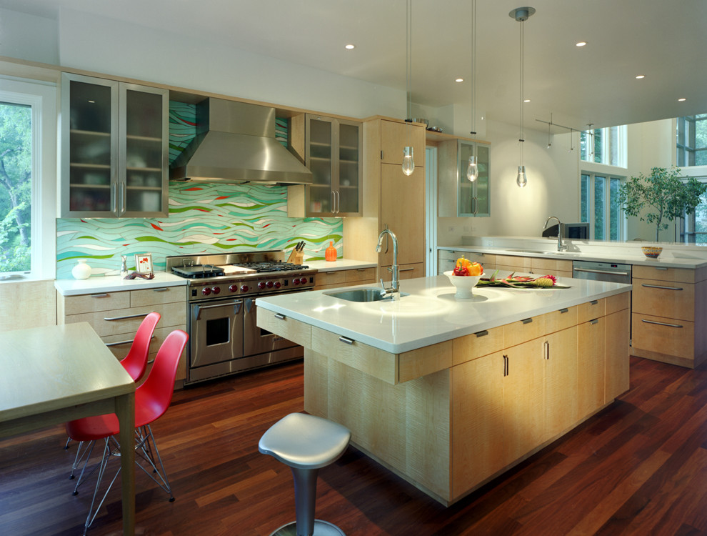 Example of a trendy l-shaped open concept kitchen design in Austin with paneled appliances, multicolored backsplash, flat-panel cabinets, light wood cabinets, quartz countertops and an undermount sink