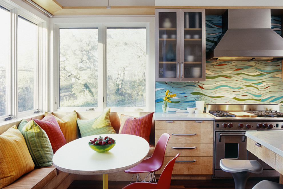 Réalisation d'une cuisine design en bois brun avec un électroménager en acier inoxydable, un placard à porte plane et une crédence multicolore.