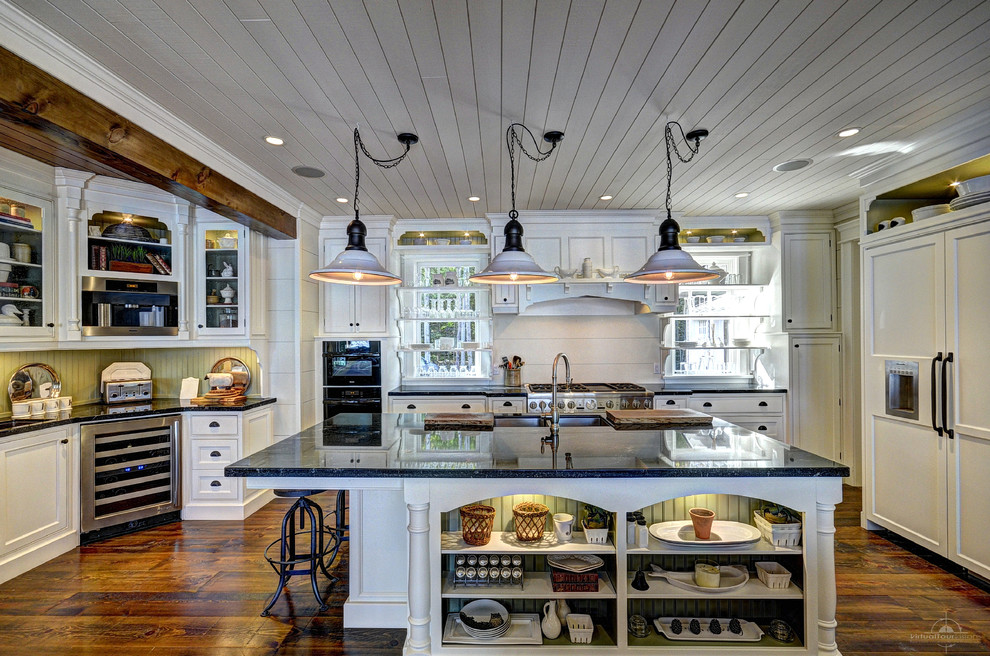 Bild på ett rustikt kök, med en dubbel diskho, vita skåp, integrerade vitvaror, en köksö, mörkt trägolv och luckor med profilerade fronter
