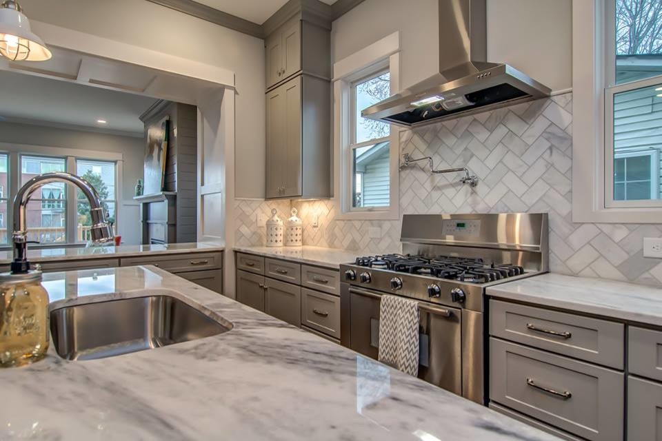 Inspiration for a mid-sized transitional l-shaped dark wood floor eat-in kitchen remodel in Raleigh with an undermount sink, shaker cabinets, gray cabinets, quartz countertops, gray backsplash, stone tile backsplash, paneled appliances and an island