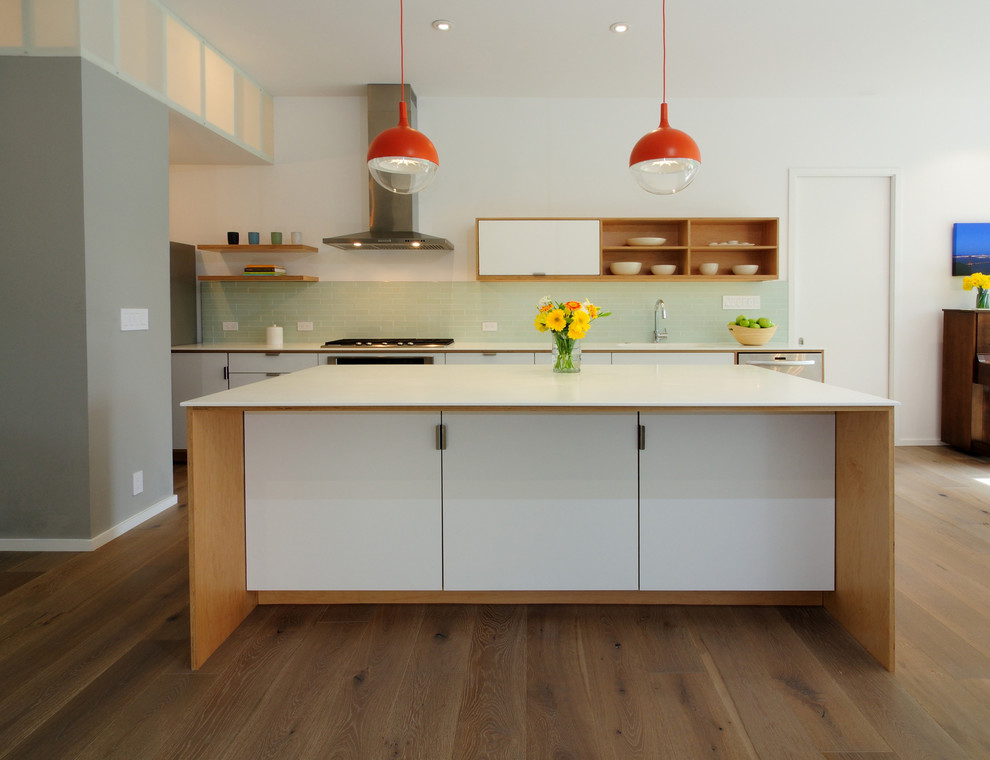 Modern inredning av ett mellanstort linjärt kök med öppen planlösning, med en integrerad diskho, släta luckor, bänkskiva i koppar, grönt stänkskydd, stänkskydd i keramik, rostfria vitvaror, mellanmörkt trägolv och en köksö