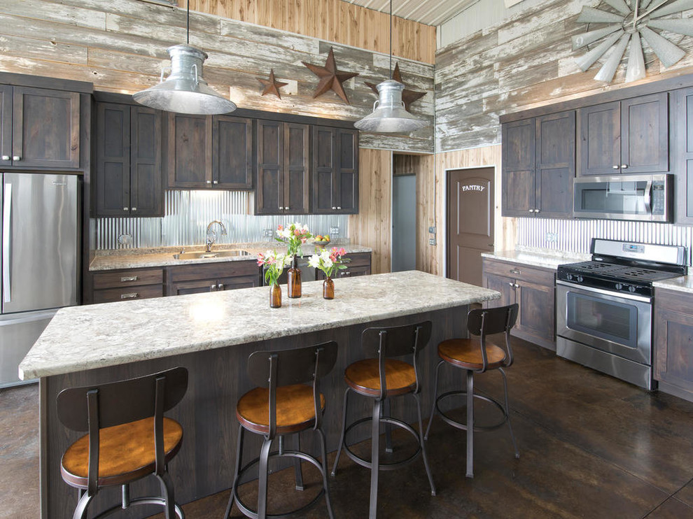 Photo of a rustic l-shaped kitchen in Minneapolis with shaker cabinets, dark wood cabinets, metallic splashback, metal splashback, stainless steel appliances, concrete flooring, an island and brown floors.