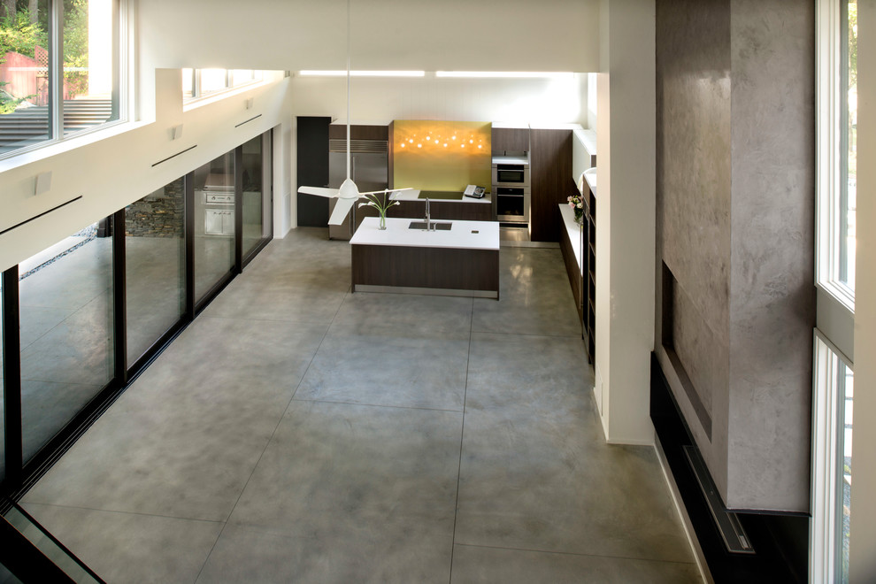 Foto di una cucina moderna di medie dimensioni con lavello sottopiano, ante lisce, ante in legno bruno, paraspruzzi giallo, elettrodomestici in acciaio inossidabile e pavimento in cemento