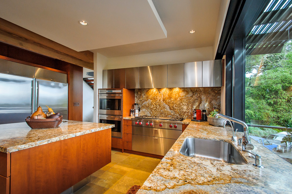 Cette image montre une grande cuisine ouverte minimaliste en U et bois brun avec un évier encastré, un placard à porte plane, un plan de travail en granite, un électroménager en acier inoxydable et îlot.