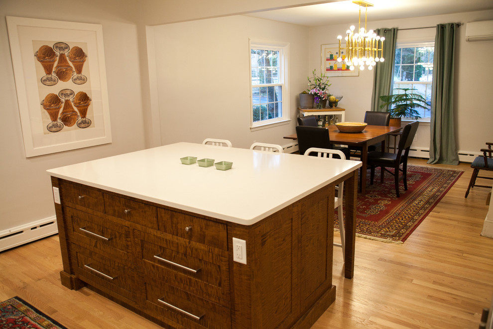 Klassisk inredning av ett mellanstort kök, med en undermonterad diskho, luckor med infälld panel, vita skåp, bänkskiva i kvarts, grått stänkskydd, rostfria vitvaror, ljust trägolv och en köksö