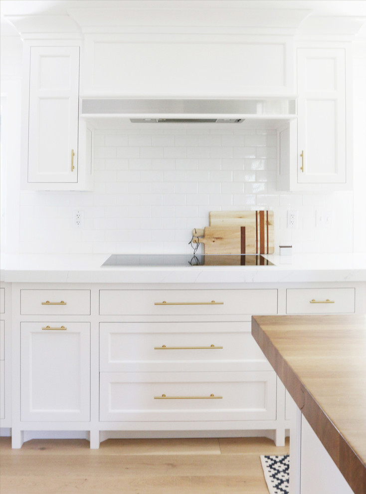 Inspiration pour une arrière-cuisine traditionnelle avec des portes de placard blanches, plan de travail en marbre, une crédence blanche, parquet clair et îlot.