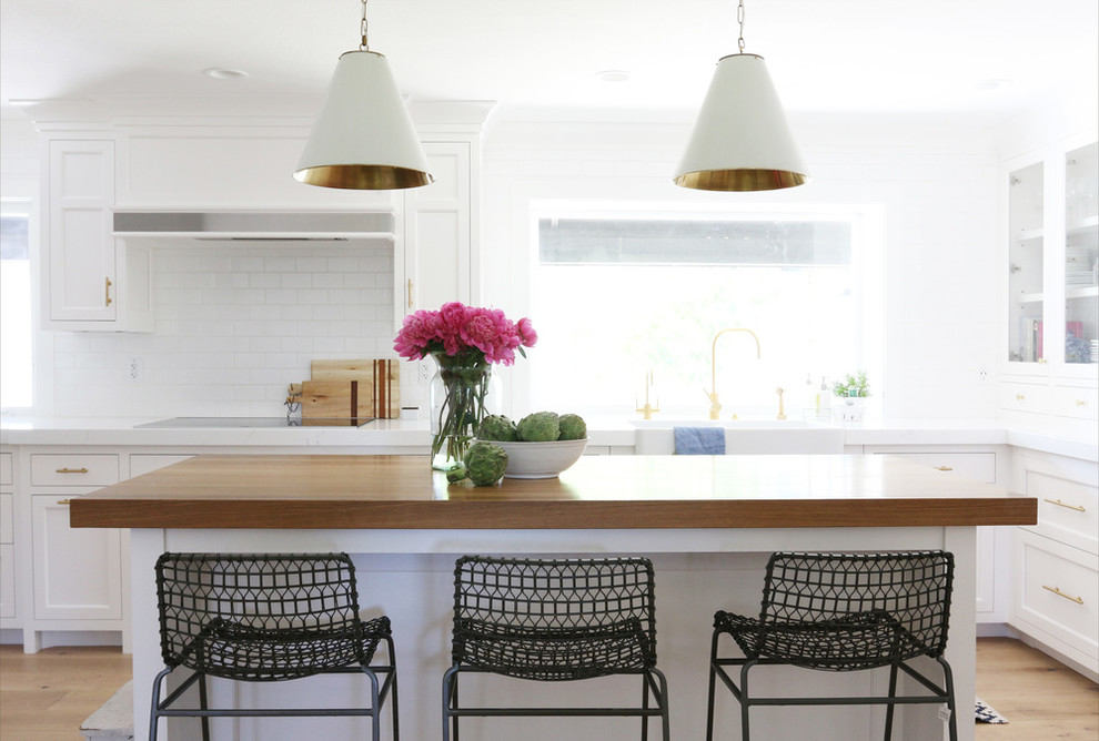 Immagine di una cucina con ante bianche, top in marmo, paraspruzzi bianco e parquet chiaro