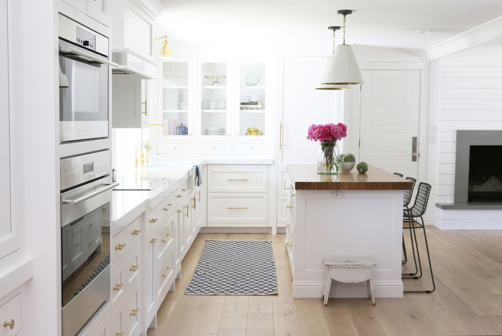 Exemple d'une arrière-cuisine avec des portes de placard blanches, plan de travail en marbre, une crédence blanche, parquet clair et îlot.