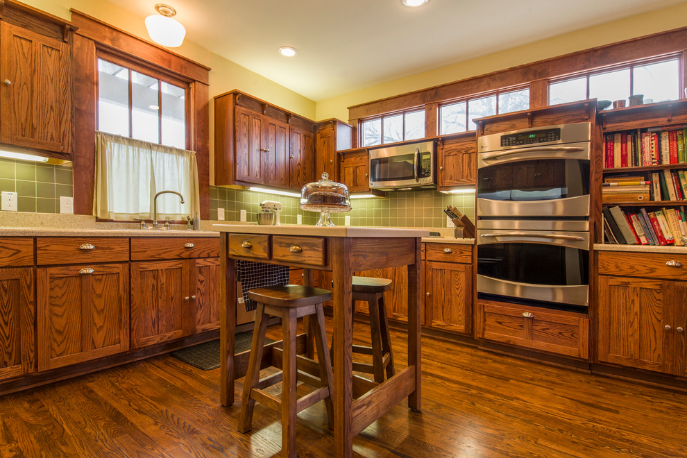 Rustikale Küche mit Schrankfronten im Shaker-Stil, dunklen Holzschränken, Küchenrückwand in Grün, Küchengeräten aus Edelstahl und dunklem Holzboden in Dallas