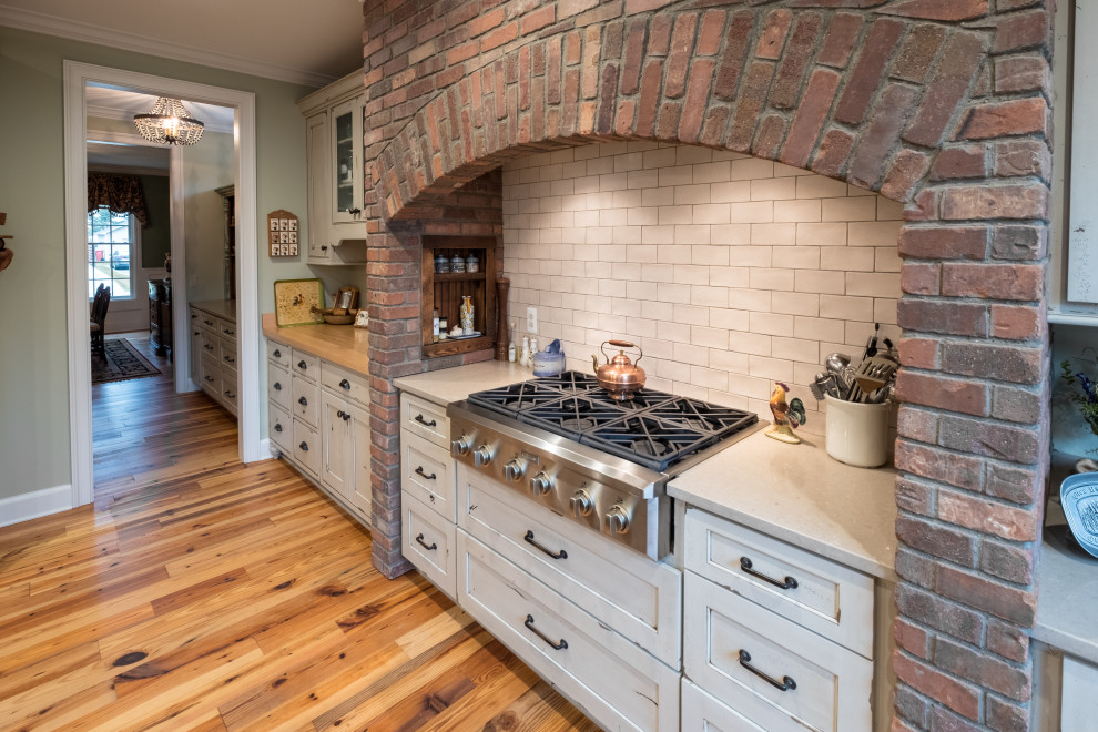 Foto på ett stort lantligt vit kök, med luckor med infälld panel, skåp i slitet trä, bänkskiva i kvarts, rostfria vitvaror, ljust trägolv, en köksö och brunt golv