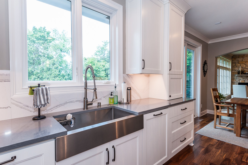 Exempel på ett stort lantligt kök, med en rustik diskho, luckor med infälld panel, vita skåp, marmorbänkskiva, vitt stänkskydd, stänkskydd i sten, integrerade vitvaror, mörkt trägolv, en köksö och brunt golv