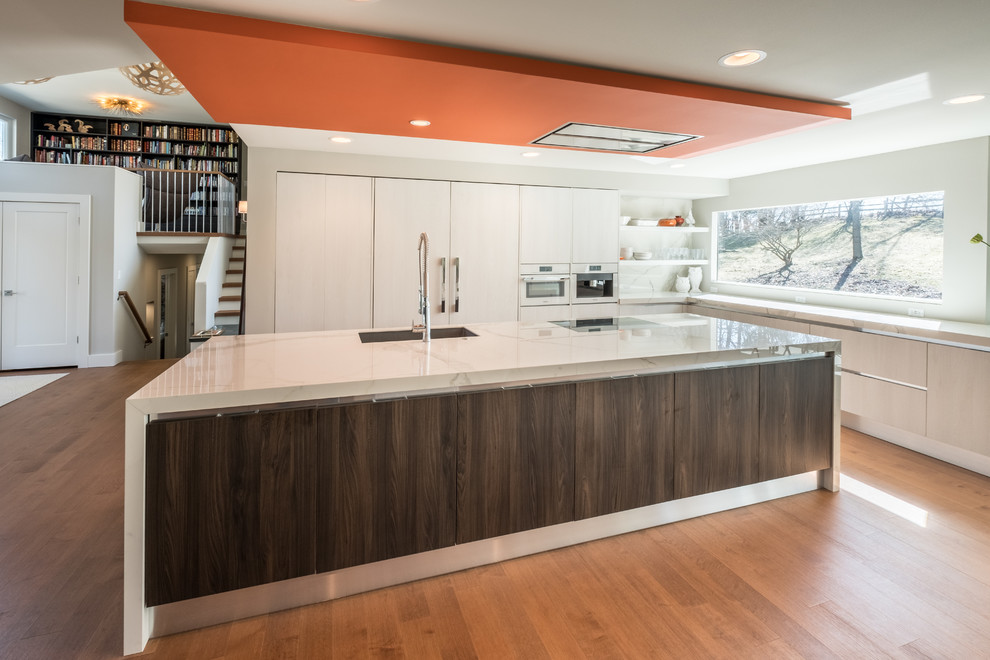 Design ideas for a medium sized contemporary l-shaped open plan kitchen in Detroit with a submerged sink, flat-panel cabinets, white cabinets, quartz worktops, stainless steel appliances, medium hardwood flooring, an island, brown floors, white splashback and marble splashback.