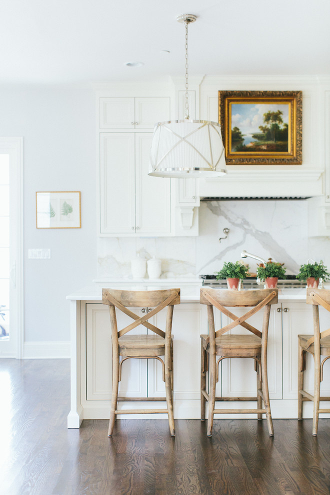 Example of a transitional galley medium tone wood floor eat-in kitchen design in Chicago with white cabinets, gray backsplash, an island and marble backsplash