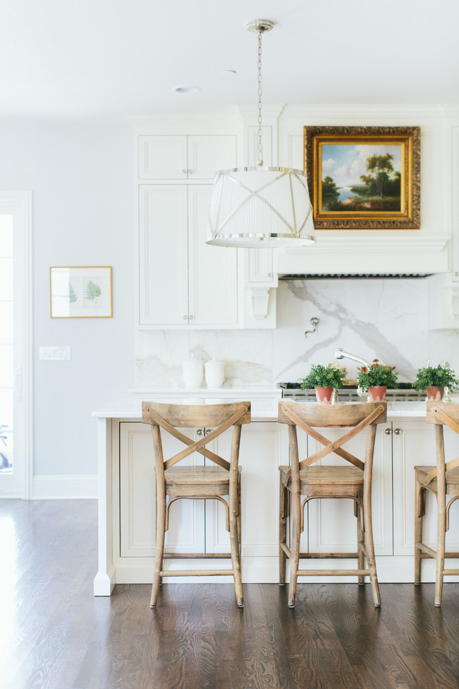 На фото: параллельная кухня в стиле неоклассика (современная классика) с обеденным столом, белыми фасадами, серым фартуком, паркетным полом среднего тона, островом и фартуком из мрамора