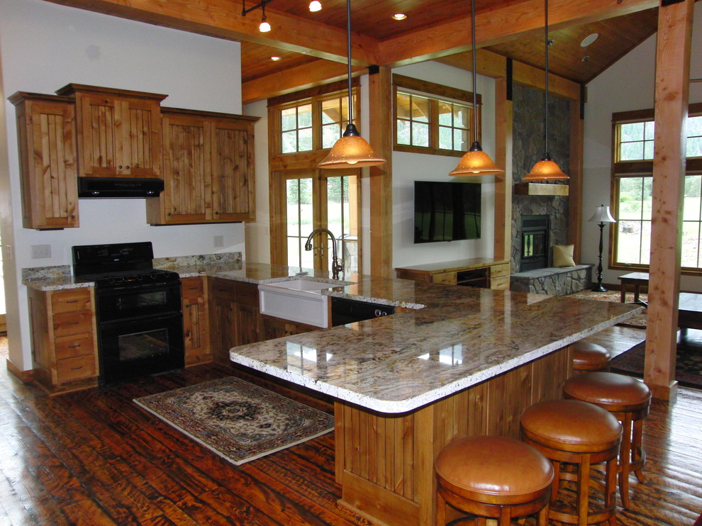 This is an example of a large rustic kitchen/diner in Tampa with a belfast sink, beaded cabinets, medium wood cabinets, granite worktops, black appliances, medium hardwood flooring and no island.