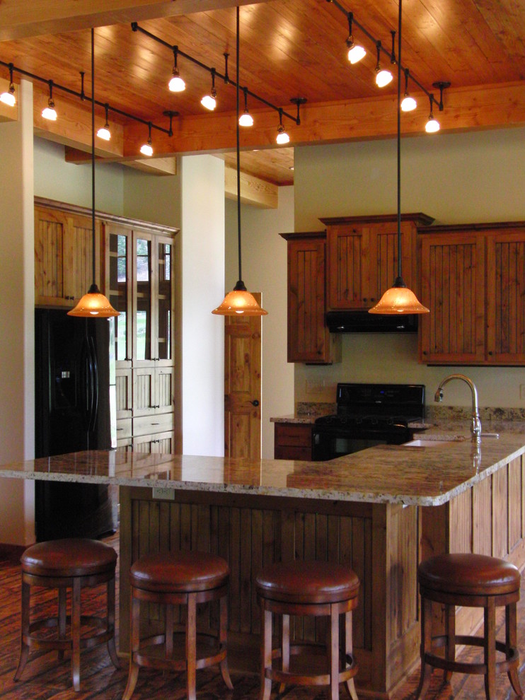 Rustik inredning av ett stort kök och matrum, med en rustik diskho, luckor med profilerade fronter, skåp i mellenmörkt trä, granitbänkskiva, svarta vitvaror och mellanmörkt trägolv