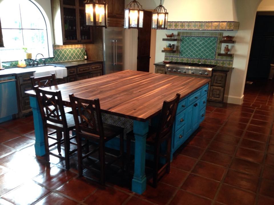 Photo of a large mediterranean u-shaped kitchen/diner in Houston with raised-panel cabinets, blue cabinets, wood worktops, multi-coloured splashback, ceramic splashback, stainless steel appliances, terracotta flooring, an island, brown floors and brown worktops.