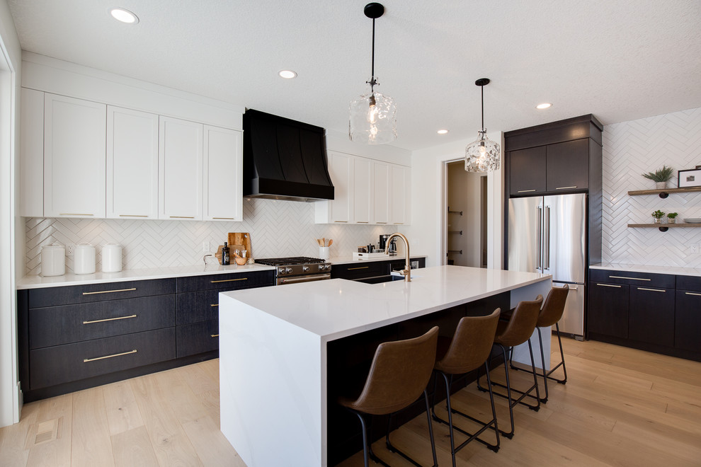 Klassische Küche in L-Form mit flächenbündigen Schrankfronten, schwarzen Schränken, Küchenrückwand in Weiß, Küchengeräten aus Edelstahl, braunem Holzboden, Kücheninsel, braunem Boden und weißer Arbeitsplatte in Calgary