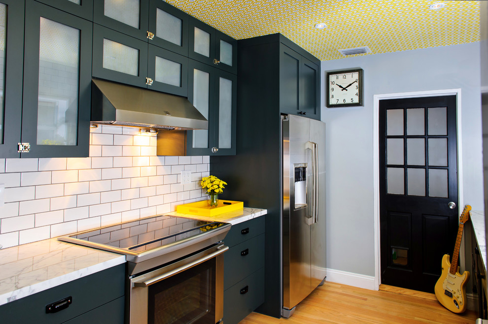 Bild på ett mellanstort funkis kök, med rostfria vitvaror, marmorbänkskiva, skåp i shakerstil, grå skåp, vitt stänkskydd, stänkskydd i tunnelbanekakel, ljust trägolv och en halv köksö