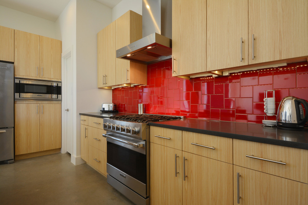 Idée de décoration pour une cuisine américaine design en L et bois clair avec un placard à porte plane, un plan de travail en quartz modifié, une crédence rouge, une crédence en céramique et un électroménager en acier inoxydable.